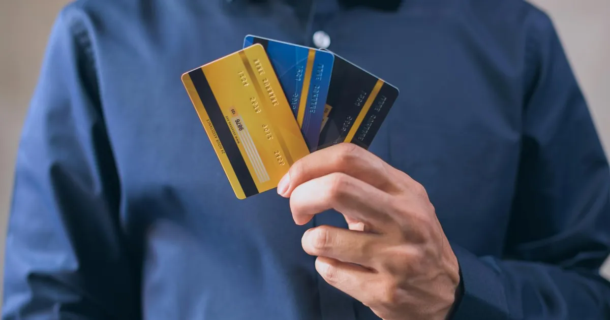 Person holding three credit cards, symbolizing finance, security, and e-commerce.