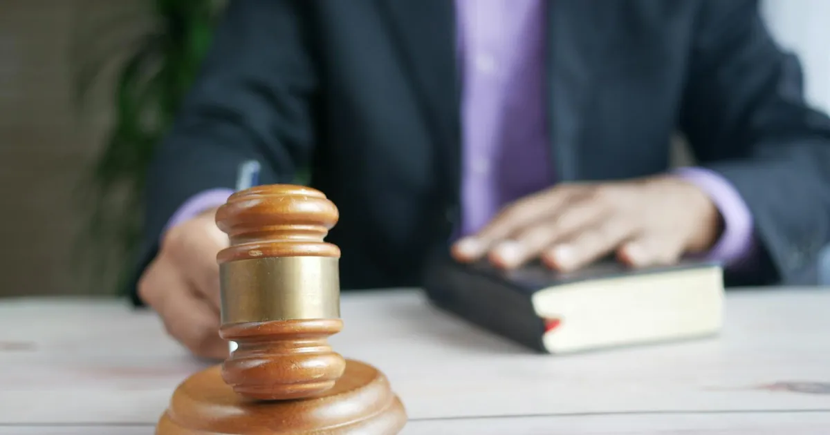 A wooden gavel and legal book represent justice in a court setting, emphasizing order and legal authority.