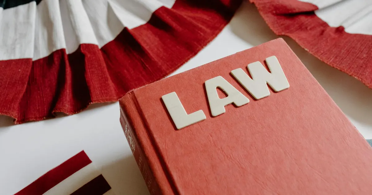 A law book with bold letters placed beside a red, white, and black decorative ribbon.