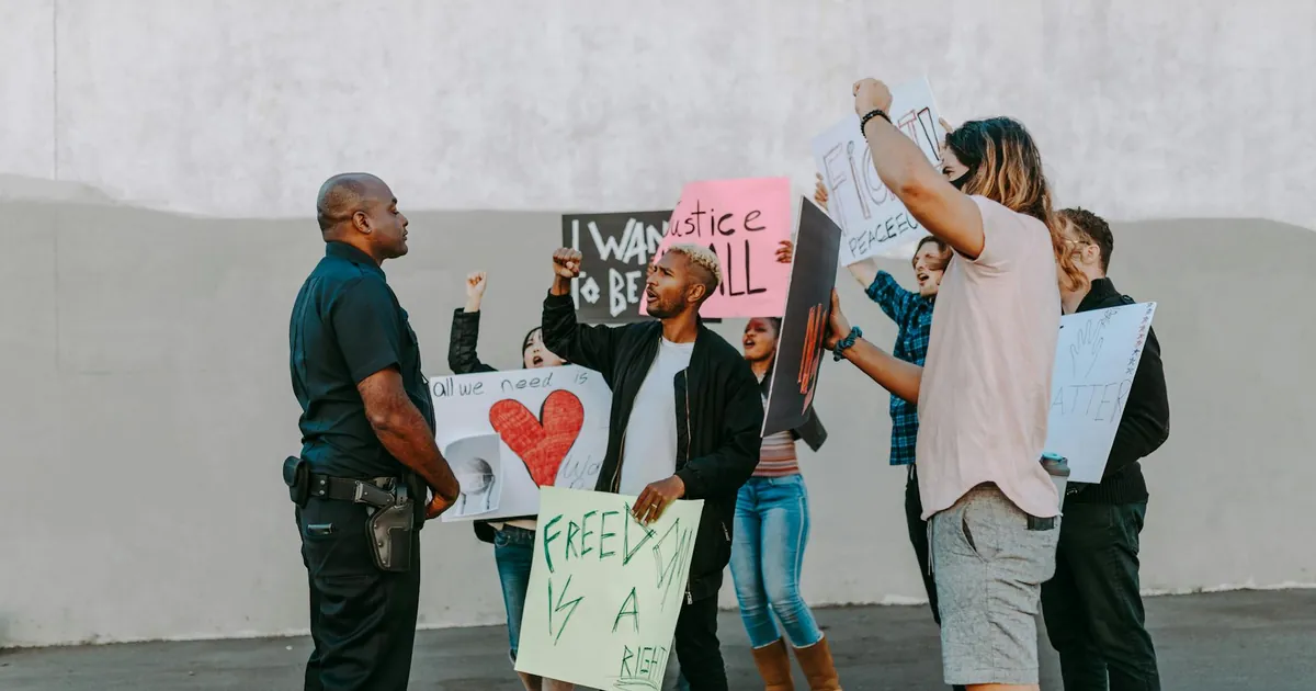 A group of diverse protesters holding signs during a peaceful demonstration outdoors.