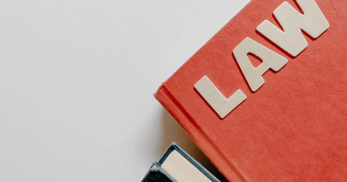 Red law textbook and dark book on white background, symbolizing education.