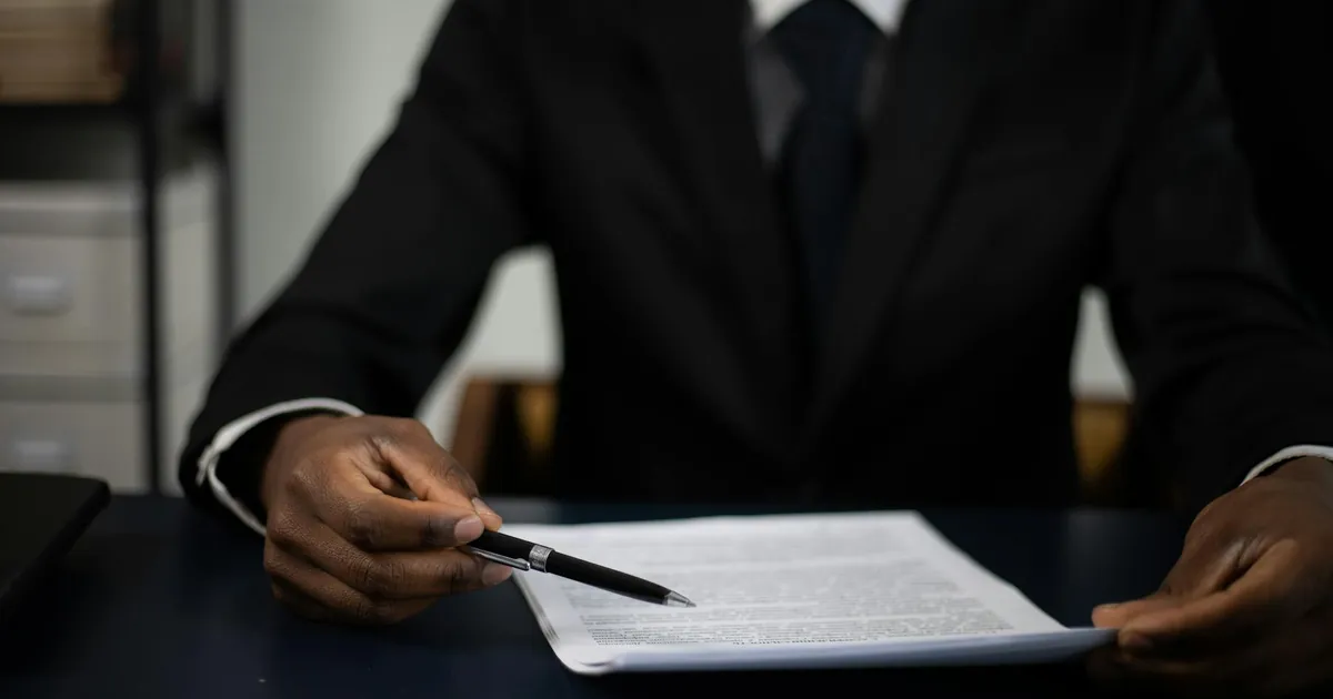 Close-up of a professional in a suit reviewing a document with focused attention.