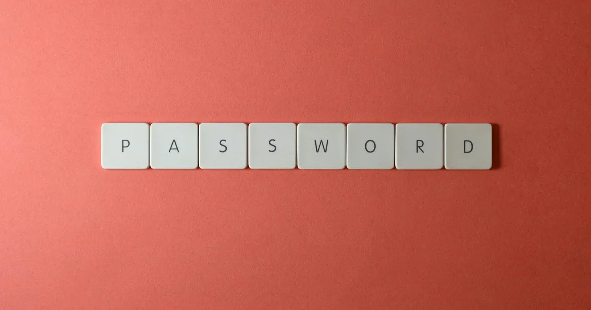 Focus on password security with white keyboard tiles spelling 'PASSWORD' on a coral background.