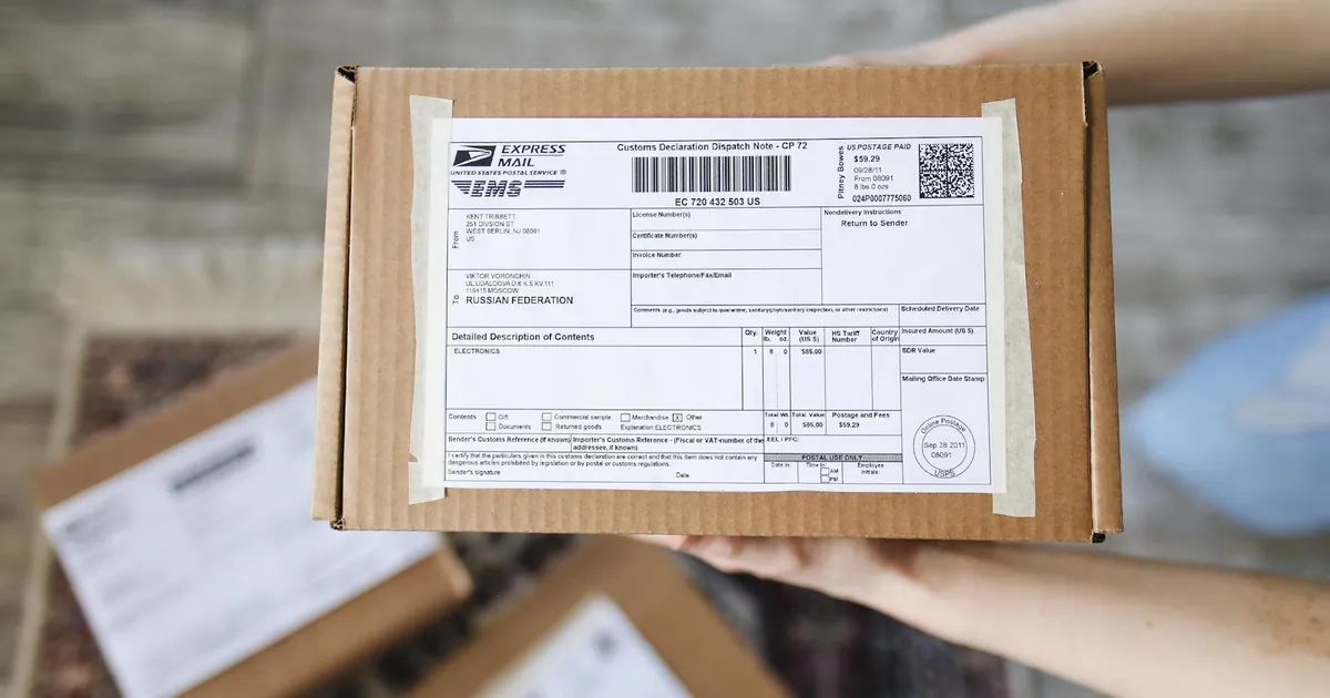 Top view of hands holding an express mail parcel with a customs declaration.