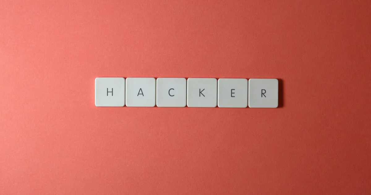 Close-up of the word 'HACKER' made with letter tiles on a red background, emphasizing cybersecurity.