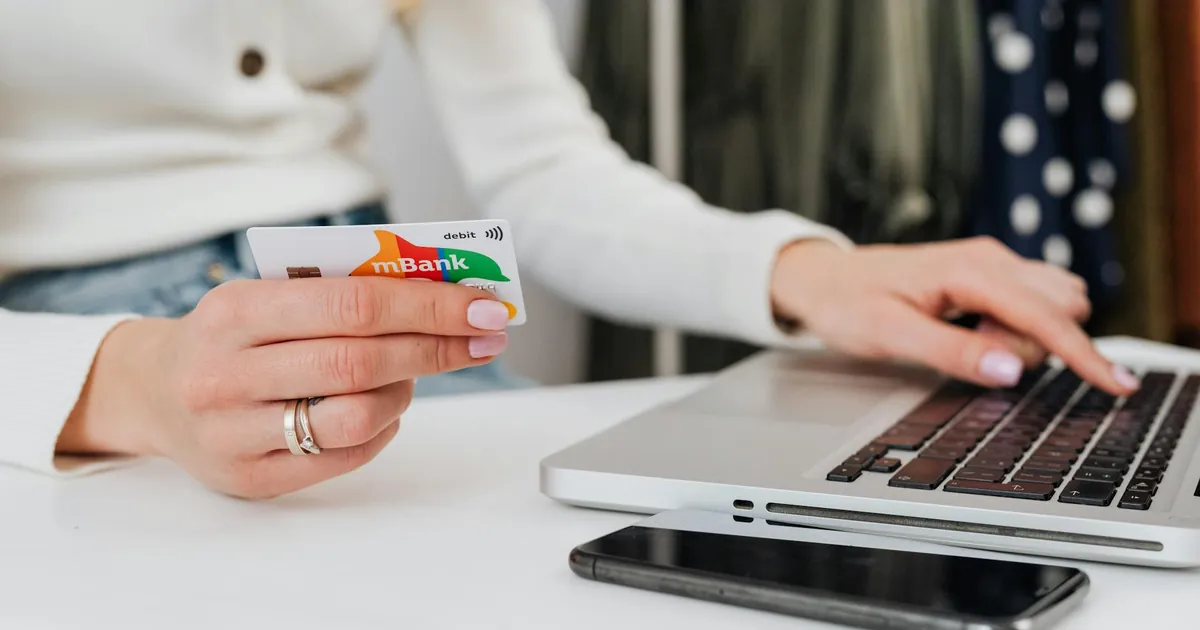 Close-up of a woman using a credit card for online shopping on a laptop, emphasizing digital transactions.