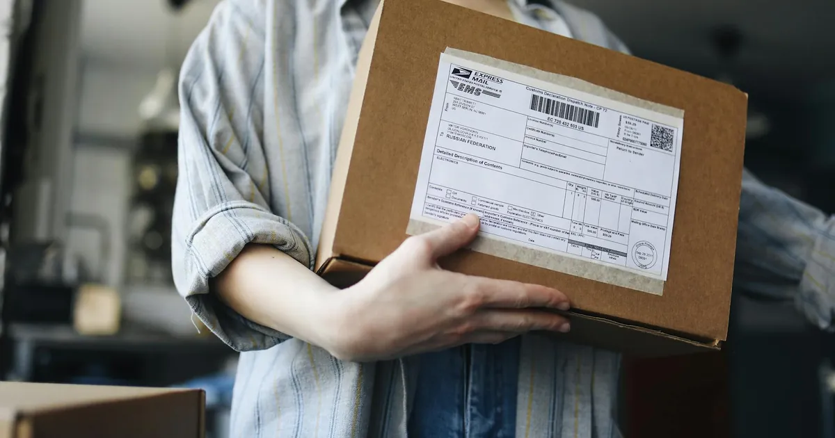 Close-up of a woman holding a parcel indoors, showcasing postal and delivery themes.