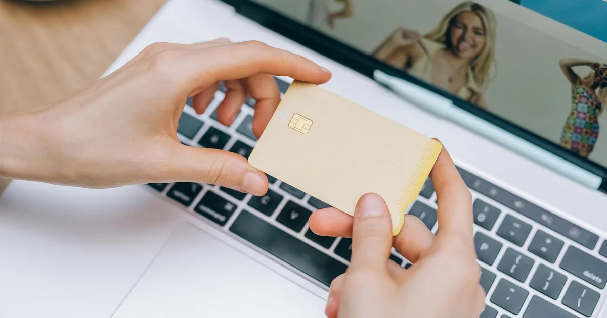 Close-up of hands holding credit card for online shopping on a laptop. Perfect for e-commerce and finance visuals.