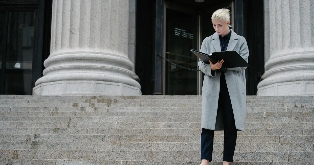 Young female professional examines documents on urban staircase
