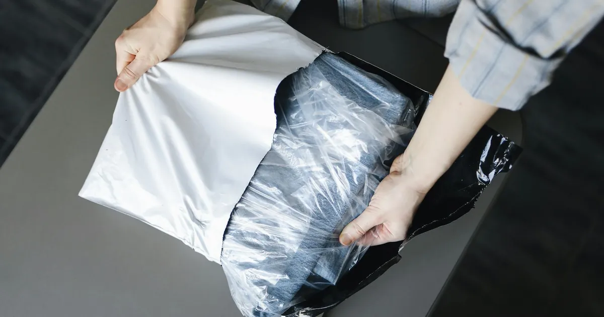 Close-up of a person unpacking a delivered parcel on a table indoors.