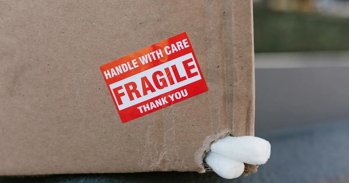 Close-up of a cardboard box with a 'fragile' sticker and packing peanuts visible.